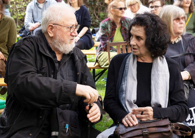 Die Künstlerin Núria Quevedo im Gespräch mit einem Mann bei der Ausstellungseröffnung “Von Anna Humpelhexe bis Zacharias Zappelbein” im LesArt-Garten